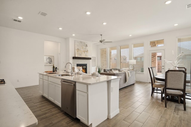 kitchen with a sink, wood tiled floor, visible vents, and stainless steel dishwasher