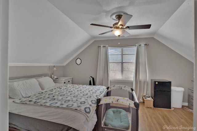 bedroom with lofted ceiling, a ceiling fan, wood finished floors, and freestanding refrigerator