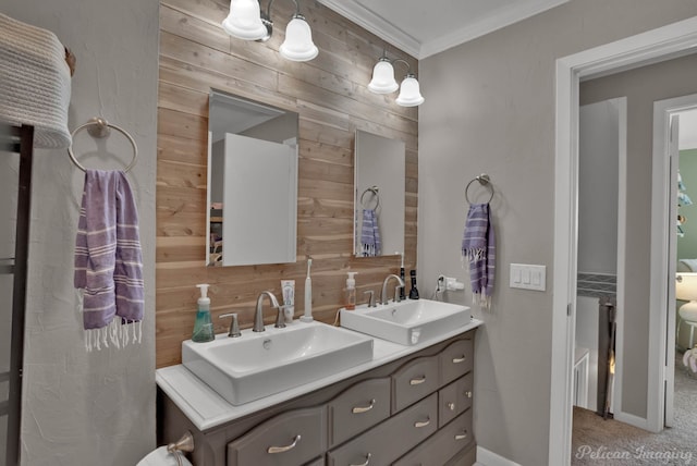 full bathroom with double vanity, crown molding, wooden walls, and a sink