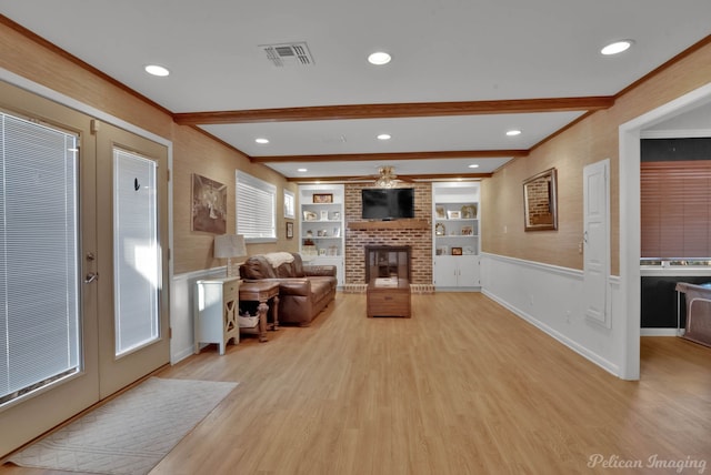 living room featuring built in shelves, beam ceiling, visible vents, and light wood-style floors