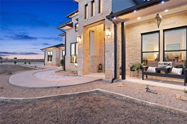 exterior entry at dusk featuring stone siding