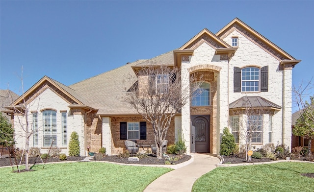 french provincial home featuring a front lawn, roof with shingles, and brick siding