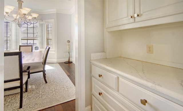 interior space with ornamental molding, dark wood-type flooring, baseboards, and a notable chandelier