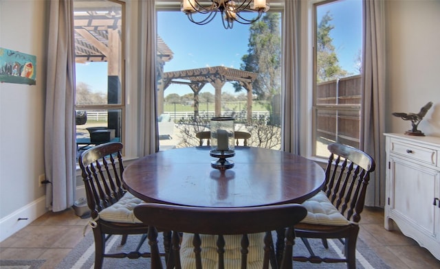 dining area with plenty of natural light, a notable chandelier, baseboards, and light tile patterned floors