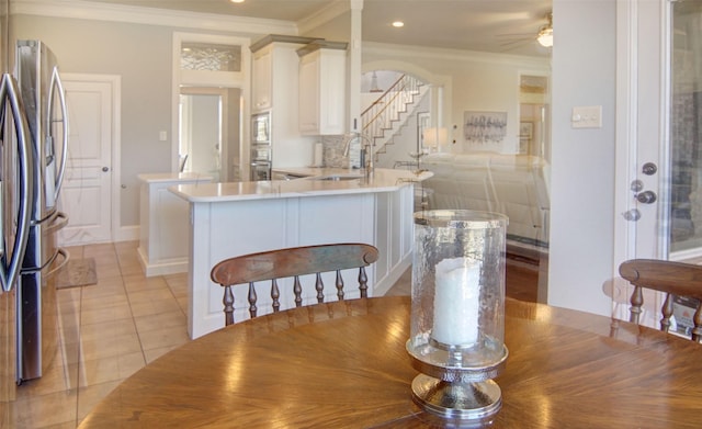 dining space with arched walkways, light tile patterned floors, recessed lighting, ornamental molding, and stairs