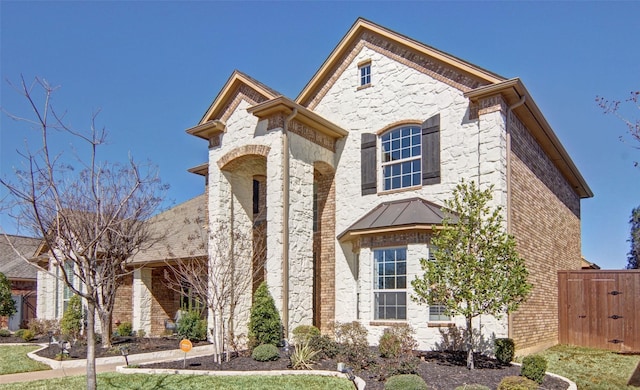 french country home with metal roof, stone siding, brick siding, and a standing seam roof