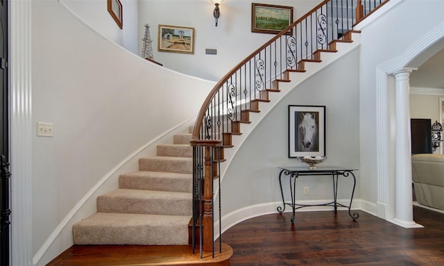 stairs featuring arched walkways, wood finished floors, visible vents, and ornate columns