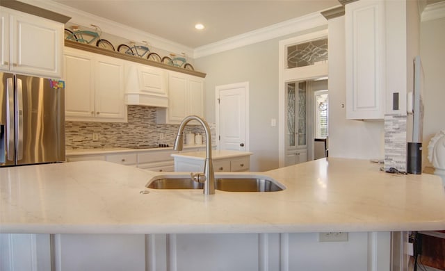 kitchen featuring crown molding, backsplash, white cabinetry, a sink, and stainless steel fridge with ice dispenser