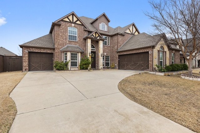 english style home featuring an attached garage, driveway, a shingled roof, and brick siding