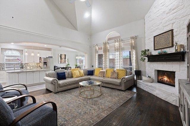 living room featuring a healthy amount of sunlight, a fireplace, arched walkways, and wood finished floors