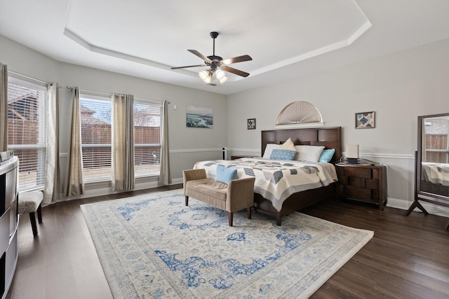 bedroom with a ceiling fan, baseboards, a raised ceiling, and dark wood-style flooring