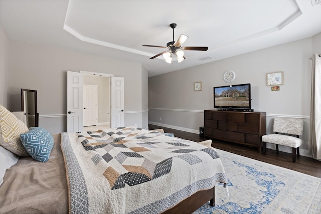 bedroom featuring baseboards, visible vents, a raised ceiling, ceiling fan, and wood finished floors