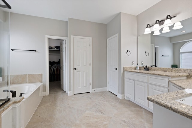 bathroom featuring a garden tub, baseboards, a walk in closet, and vanity