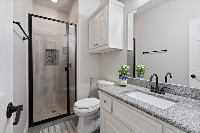 bathroom with toilet, a stall shower, and vanity