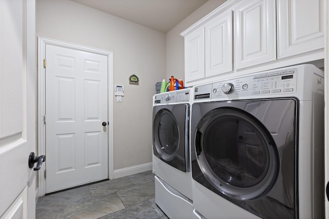 laundry area featuring stone finish floor, cabinet space, baseboards, and separate washer and dryer