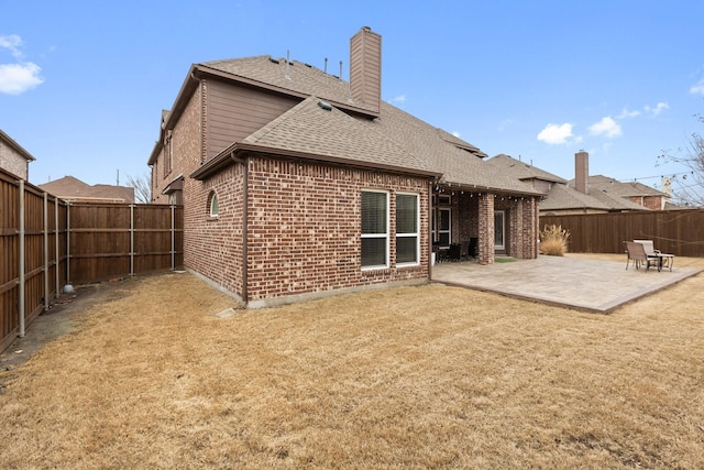 back of house with a patio, brick siding, a shingled roof, and a fenced backyard