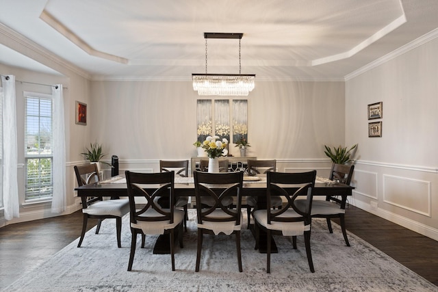 dining area with a decorative wall, wood finished floors, ornamental molding, a tray ceiling, and an inviting chandelier