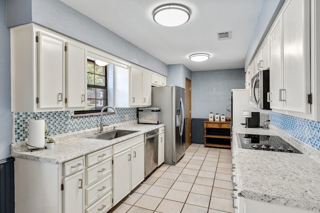 kitchen with stainless steel appliances, visible vents, white cabinetry, a sink, and light tile patterned flooring