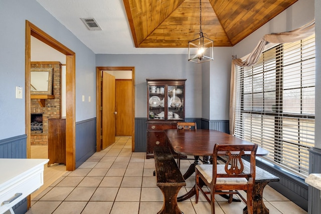 dining space featuring visible vents, light tile patterned floors, wainscoting, and wood ceiling