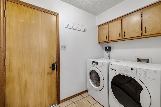 laundry area with light tile patterned floors, cabinet space, a textured ceiling, independent washer and dryer, and baseboards