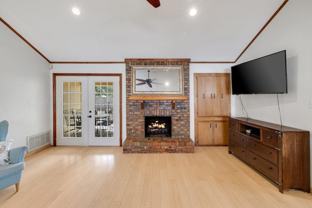 living area featuring light wood-type flooring, french doors, visible vents, and a fireplace