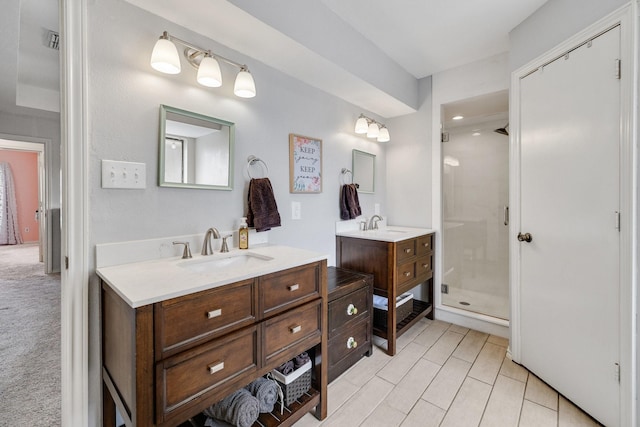 full bath featuring a stall shower, two vanities, and a sink