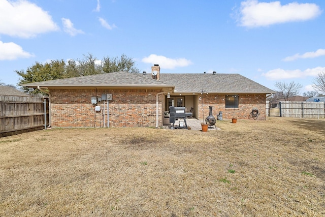 back of property with brick siding, fence, a chimney, and a lawn