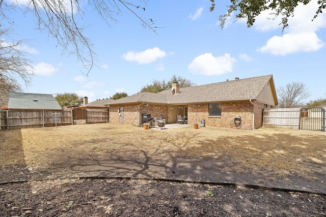 rear view of property featuring a patio area, a fenced backyard, a gate, and brick siding