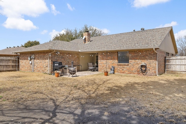 rear view of house with a patio area, a chimney, fence, and brick siding