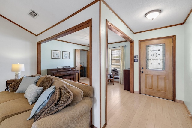 entrance foyer with baseboards, light wood-style flooring, visible vents, and crown molding