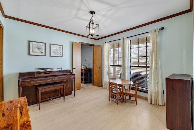 dining room with a notable chandelier, light wood finished floors, and crown molding