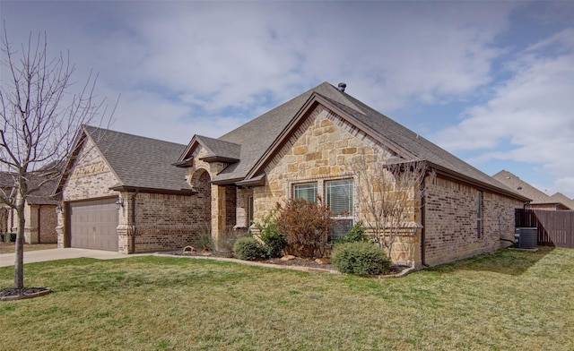 french country inspired facade with driveway, a front lawn, central AC, an attached garage, and brick siding