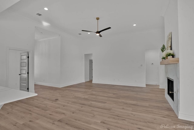 unfurnished living room with light wood-style floors, ceiling fan, a fireplace, and ornamental molding