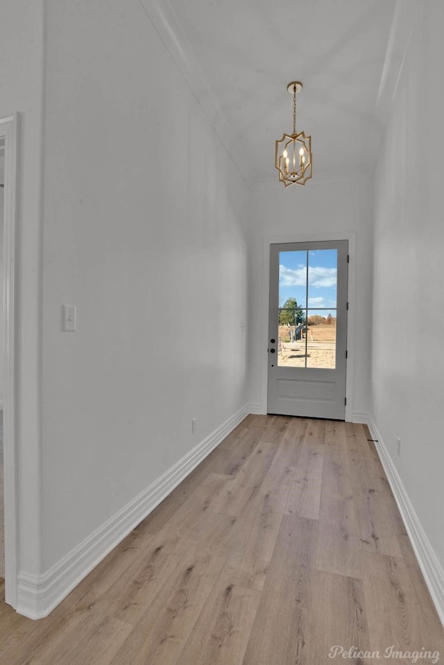 interior space featuring baseboards, vaulted ceiling, an inviting chandelier, and light wood-style floors