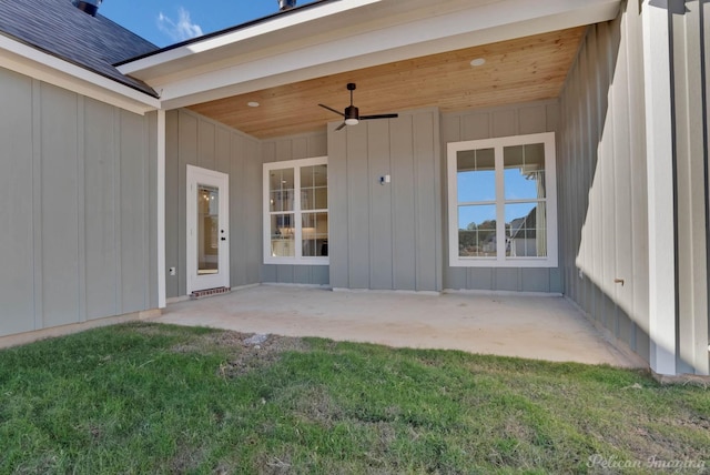 view of exterior entry with a patio area, ceiling fan, and board and batten siding