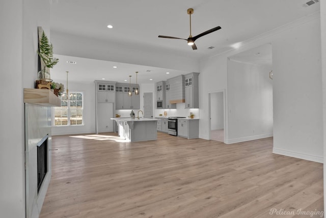 unfurnished living room featuring recessed lighting, visible vents, light wood-style floors, baseboards, and ceiling fan with notable chandelier