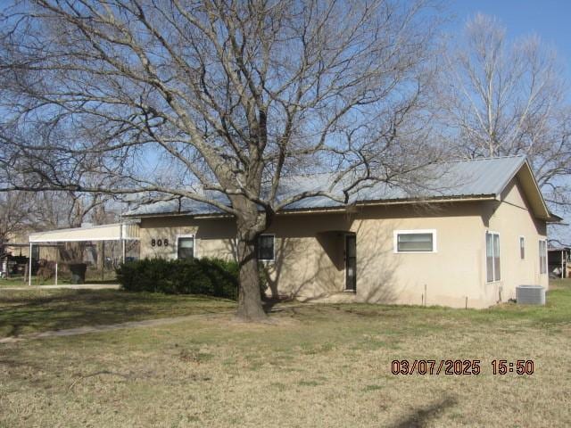 exterior space with stucco siding, metal roof, cooling unit, and a yard