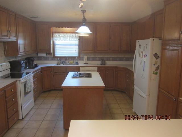 kitchen with white appliances, light tile patterned floors, a kitchen island, light countertops, and a sink