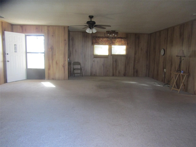 carpeted spare room with wood walls, visible vents, and a ceiling fan