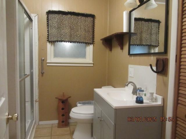 bathroom featuring toilet, a shower stall, vanity, tile patterned flooring, and baseboards