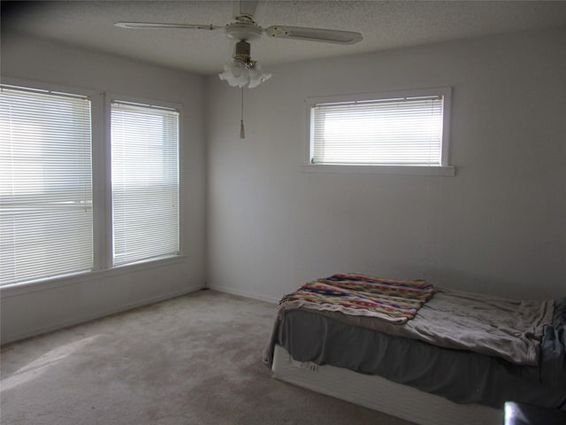 carpeted bedroom with ceiling fan and a textured ceiling