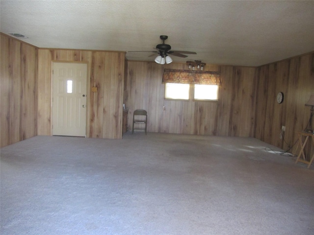 spare room with a textured ceiling, wood walls, carpet flooring, and visible vents