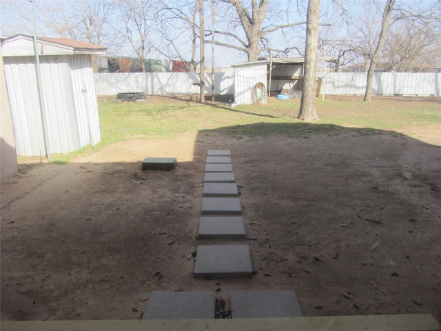 view of yard featuring a shed, an outdoor structure, and a fenced backyard