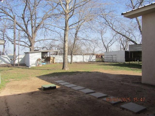 view of yard featuring an outbuilding, a storage unit, and fence