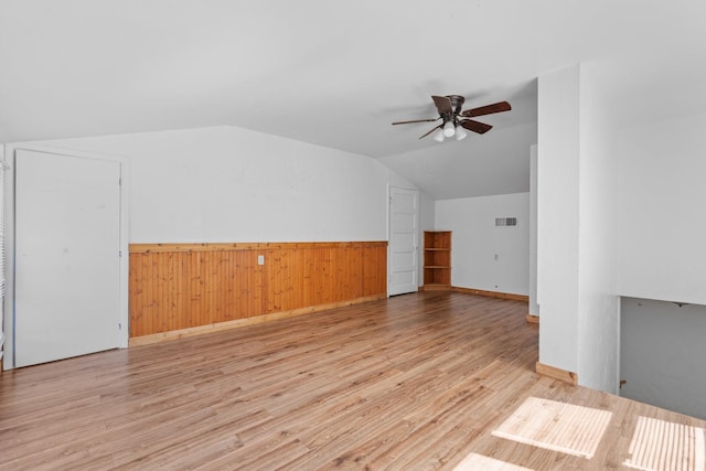 interior space featuring wood finished floors, visible vents, a ceiling fan, vaulted ceiling, and wainscoting