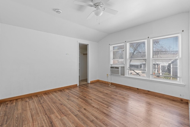 spare room with lofted ceiling, cooling unit, wood finished floors, a ceiling fan, and baseboards