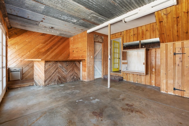 interior space with unfinished concrete flooring, a wall unit AC, and wood walls