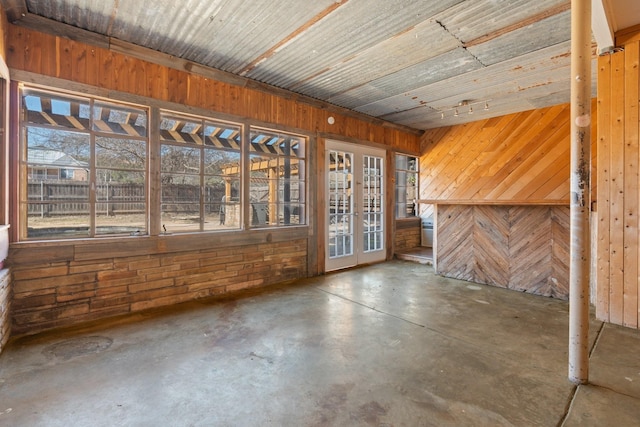 interior space featuring concrete flooring, a wealth of natural light, and wooden walls