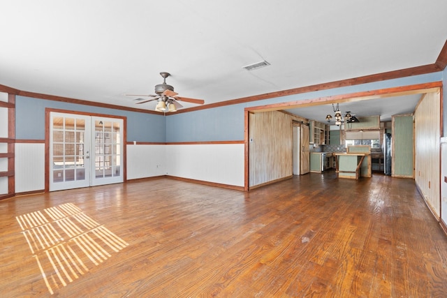 unfurnished living room with ceiling fan with notable chandelier, visible vents, french doors, hardwood / wood-style floors, and crown molding