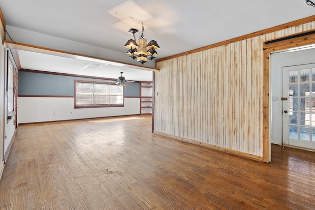 spare room with a chandelier, wainscoting, ornamental molding, and hardwood / wood-style floors